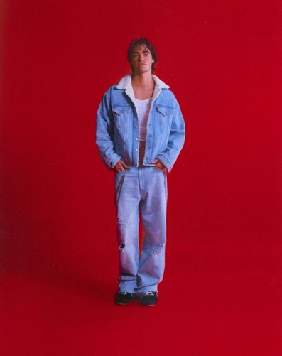 Model in double denim against a red studio backdrop